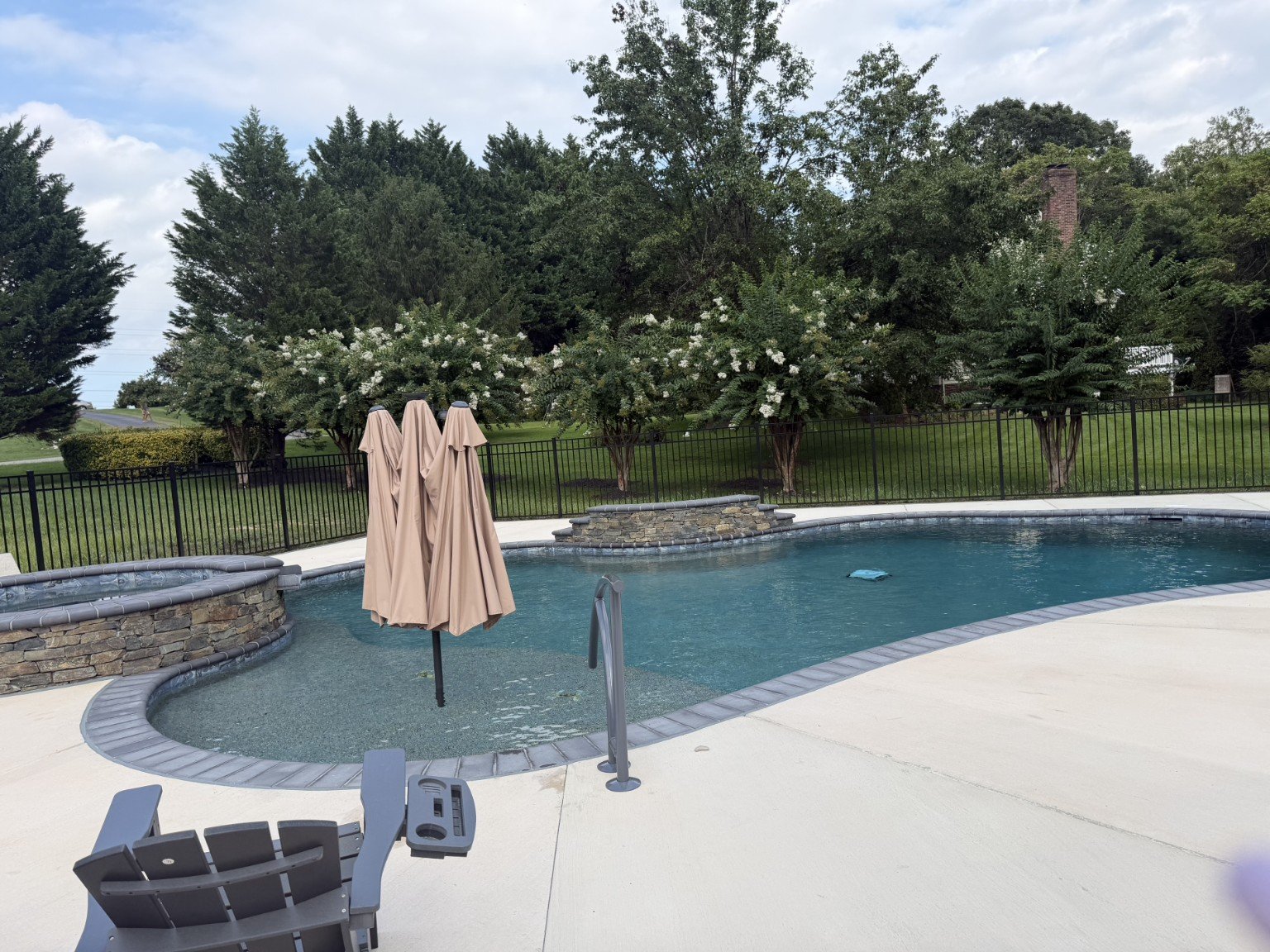 Freeform pool with raised spa and stone waterfall