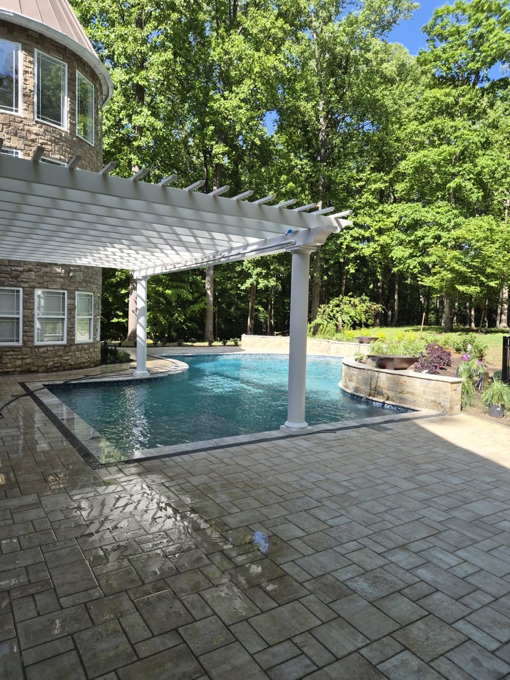 Freeform pool with white pergola and water feature